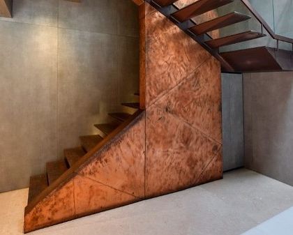 The patinated copper surface of the staircase catches the light, revealing beautiful textures and variations in color.