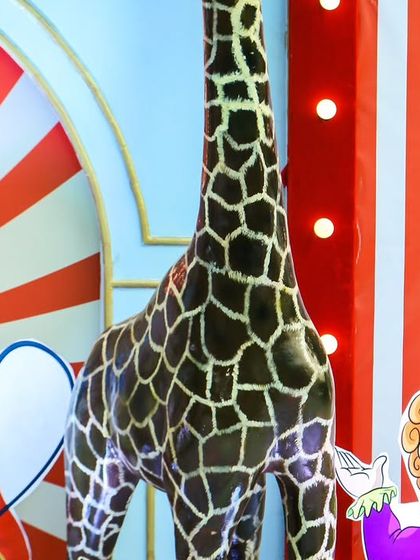 A close-up of the detailed props, including a tall giraffe and clown cutouts, that helped create an authentic carnival feel.