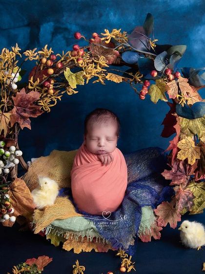 Nestled in a wreath of autumn leaves. This beautiful setup, with its rich colors and textures, is a perfect way to celebrate the arrival of a fall baby.