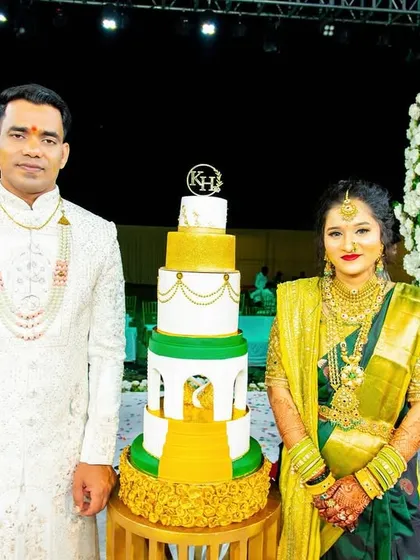 A full-length shot of the couple with their cake, capturing the grandeur of the moment.