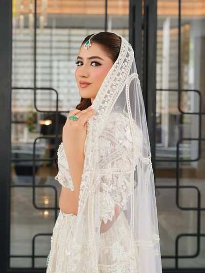 A beautiful shot of the bride looking over her shoulder, highlighting the delicate lace details of her veil. Her makeup is soft and romantic, with a focus on enhancing her natural features.