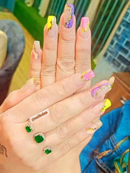 A vibrant and artistic set with a mix of yellow and pink nails, featuring abstract gold foil and purple accents.