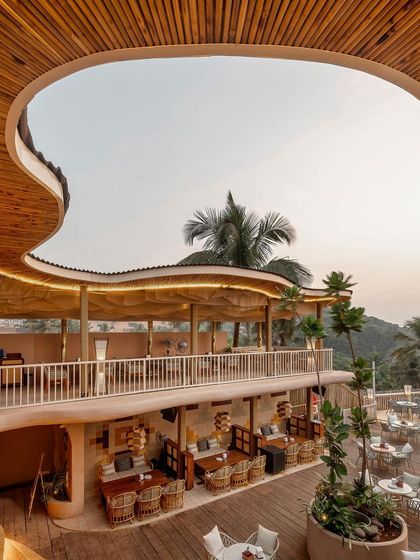 An identical shot of Dubki's architecture, highlighting the seamless integration of the structure with the surrounding palm trees and coastal landscape. The design is all about creating an immersive experience.