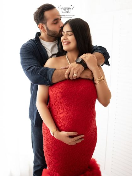 A sweet and loving embrace. This couple's portrait in the studio showcases their joy and connection, with the vibrant red lace dress adding a touch of romance.