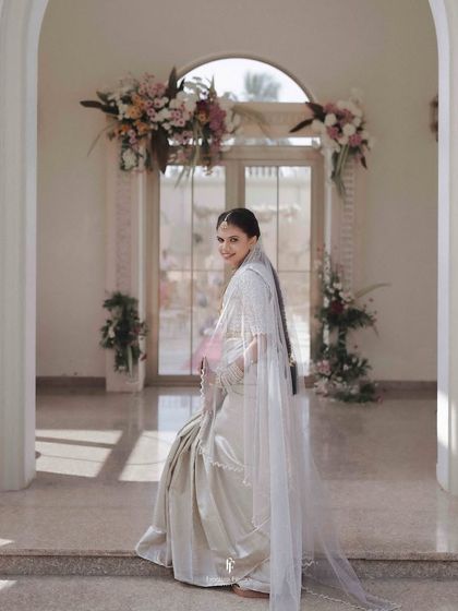 The bride in her silver saree, looking over her shoulder with a graceful turn.