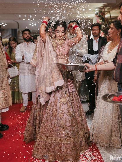 A shot of the bride during the Vidaai ceremony, throwing rice over her head as a symbol of leaving her parental home. It's a poignant and traditional moment.