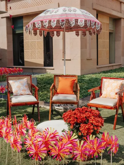 A seating nook under a hand-painted parasol, surrounded by colorful pinwheels and flowers, creating a charming spot for guests to relax.