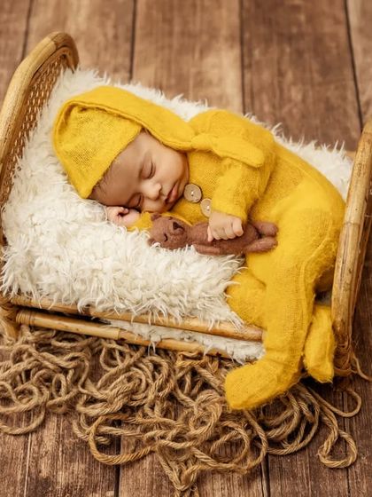 A full-length view of the baby sleeping on the rustic bed prop, creating a warm and timeless newborn photo.