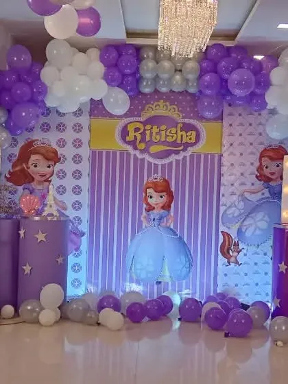 A 'Sofia the First' themed birthday party in her signature purple color. The decor includes multiple character cutouts, a custom backdrop, and extensive balloon work to create a magical castle feel.