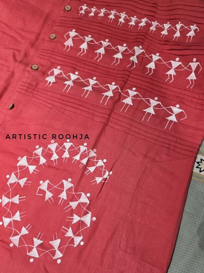 A detailed view of the Warli painting on a red kurta. You can see the characteristic stick figures holding hands and dancing, a motif that represents unity and joy in this beautiful Indian folk art form.