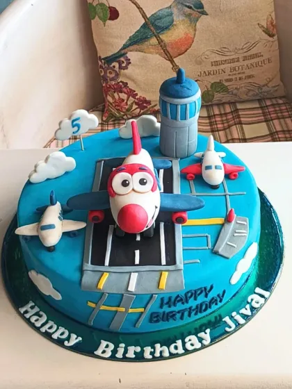 An airplane-themed cake ready for takeoff, with a cute cartoon plane on a runway, clouds, and a control tower for a 5th birthday.