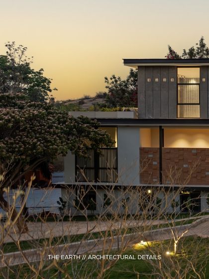 The building's profile against the sunset. The multi-level design, featuring a mix of plaster, stone, and large windows, is composed to create a visually interesting form that changes with the light throughout the day.