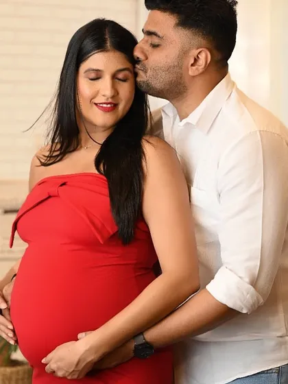 A loving kiss on the forehead in this sweet maternity portrait. The vibrant red dress adds a pop of color to the studio session.
