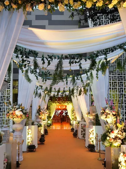 This dreamy entrance features a canopy of white drapes and hanging greenery, creating a magical, forest-like pathway into the event space.