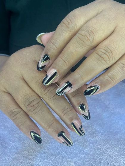 A modern black and gold design on almond-shaped nails.