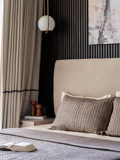 A detail shot of the bedside corner, showing the elegant globe pendant light and the texture of the curtains. The mix of materials creates a rich and layered look.