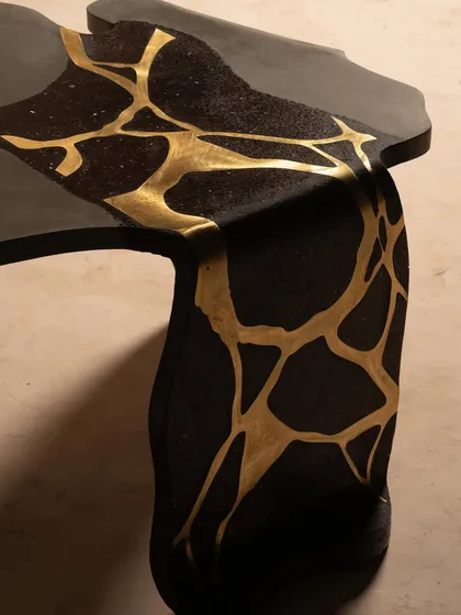 Bold black concrete meets luxurious gold brass inlay in this table from our Coral Collection. The design is inspired by the fluid, organic movement of coral, creating a piece that is both sculptural and functional.