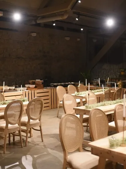 Long, rustic wooden tables set for an intimate dinner. The simple elegance of the table runners and candles created a warm and inviting atmosphere in the industrial-chic venue.