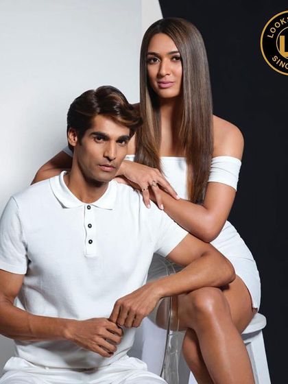 A stylish couple portrait showing off fresh hair color for both men and women. His hair is a natural brown, while hers is a sleek, straight look with subtle highlights.