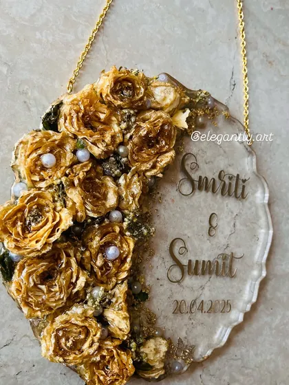 This wall-hanging frame is a beautiful way to preserve a wedding varmala. The golden roses and pearls create a luxurious feel, perfectly complementing the couple's names and wedding date.