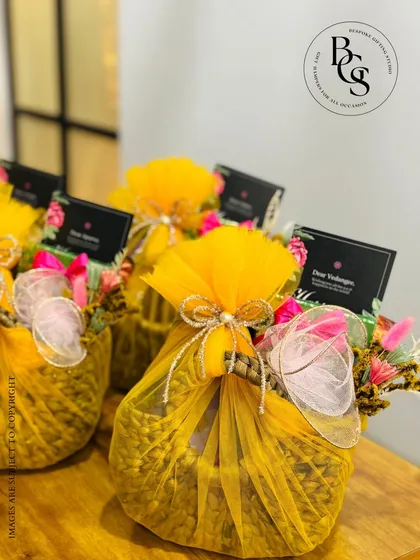 Bright and cheerful gift baskets wrapped in vibrant marigold-yellow tulle. Adorned with delicate flowers and personalized tags, these hampers are designed to bring a burst of sunshine to any celebration, be it a wedding or a festival.