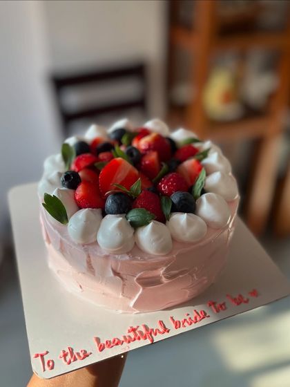 A beautiful cake for a bride-to-be. The pink strawberry buttercream is topped with a mix of fresh strawberries and blueberries and dollops of meringue.