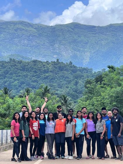 A group photo on a bridge, with the lush green mountains behind.