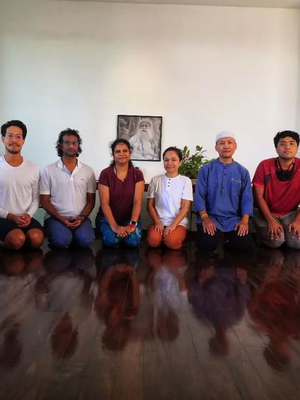 Participants kneeling in Vajrasana after a session. The polished floor reflects the stillness in the room, a common experience after the harmonizing effects of the Surya Kriya practice.