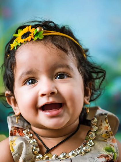 A bright, happy smile from a sitter session. The colorful background and cheerful sunflower headband add to the joyful mood of this photo.