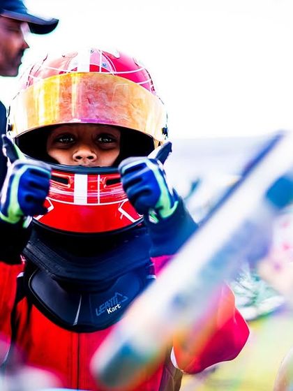 A young driver gives a thumbs up, full of enthusiasm.