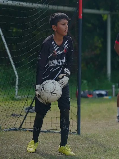 A young goalkeeper, focused and fearless, ready for action between the posts during a Delhi Youth League match.
