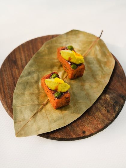 Kothimbir vadi, a classic Maharashtrian snack, is presented on a dried leaf. This small bite is packed with flavour, showcasing how we honour tradition while adding our own inventive touch.