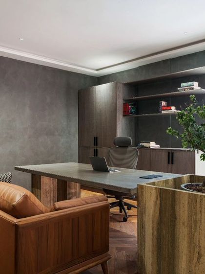 The MD's cabin at Campus Biovet, featuring a beautiful giant Bonsai in a custom travertine planter as part of the work desk. The room is simple and functional, with dark, textured walls and a large window providing ample natural light.