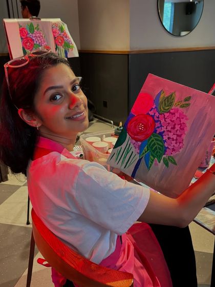 A participant at a cafe workshop, happy with her finished floral piece. Every effort counts, and every artwork is a success.