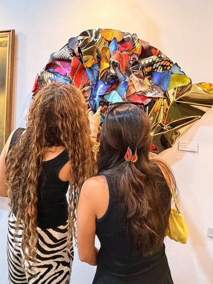 Two visitors admiring "Wings of Resilience" at an art gallery, drawn in by the vibrant colors and complex form.