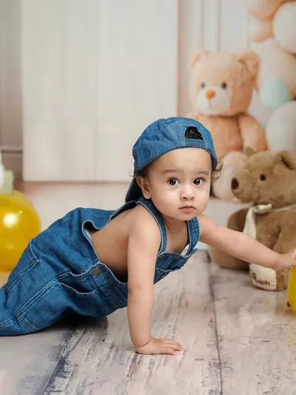 On the move! This crawling shot shows a different perspective of the birthday boy exploring his fun, themed setup with denim overalls and yellow balloons.