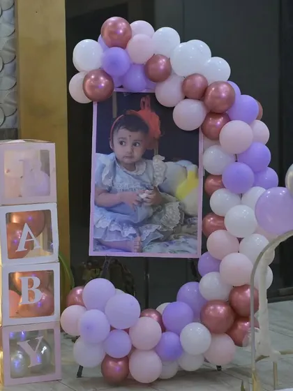 A sweet photo display for Vamika, framed by a crescent-shaped balloon arrangement and "BABY" blocks.