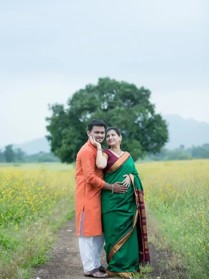 An expecting couple stands together in a vast field of yellow wildflowers, dressed in beautiful traditional Indian attire. This outdoor maternity portrait captures a serene and classic pose, highlighting their bond against a natural, picturesque backdrop.
