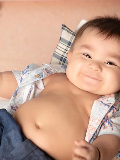 The sitter milestone, usually around six months, is filled with the most infectious smiles and blossoming personalities. This little one's cheerful grin during his beach-themed sitter session is a perfect example of the happy moments I aim to capture.