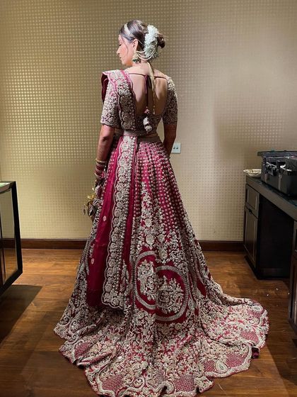The full bridal look from the back, showing how the floral bun hairstyle completes the stunning silhouette of the bride in her heavily embroidered lehenga.