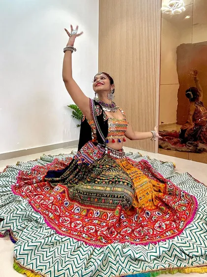 Looking up with a graceful hand gesture, this photo captures the elegance of the dance and the outfit. The backless blouse adds a modern touch.