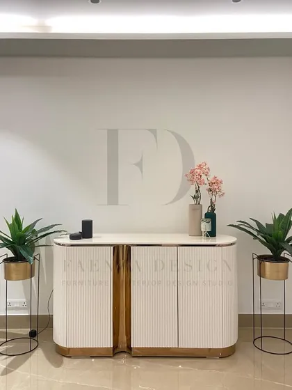 A beautiful custom console designed for a foyer. This piece features a curved, fluted body in a white Duco finish, accented with a rose-gold metallic finish, creating a warm and welcoming first impression.
