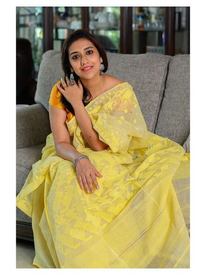 A comfortable and elegant seated pose on a couch, showcasing the saree in a natural, everyday context.