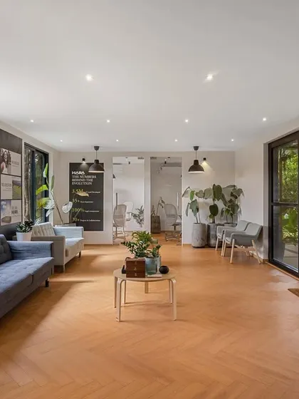 A wide shot of the container office's interior, showcasing the open and flexible layout. The herringbone wood flooring and minimalist furniture create a stylish and professional environment.