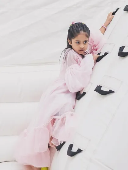 A young girl confidently climbs the handholds on our inflatable wall, showcasing the safe and engaging design of our equipment.