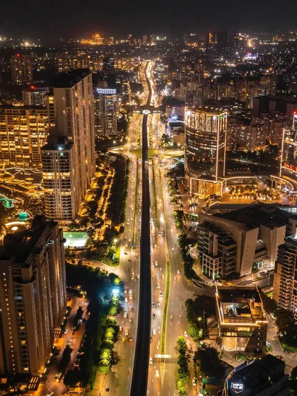 An aerial night shot looking down the illuminated spine of Golf Course Road in Gurgaon, capturing the energy of the city.
