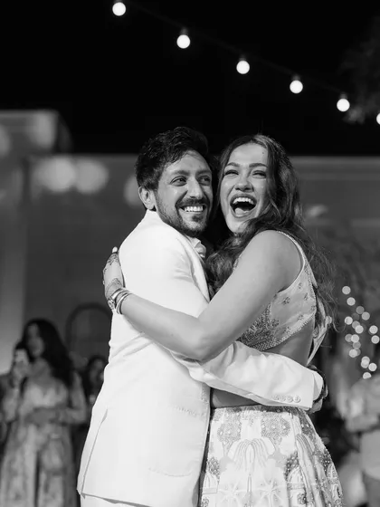 A black and white shot capturing the pure, uninhibited laughter of a couple on their sangeet night. This is what true celebration looks like.