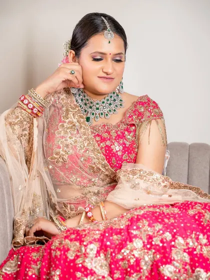 A quiet, seated moment that exudes grace. The minimal makeup allows the bride's natural beauty and the vibrant pink of her lehenga to take center stage.