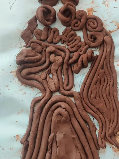 A beautiful silhouette filled with intricate coils of clay, creating a sense of flowing hair. This piece showcases a wonderful use of texture and pattern.