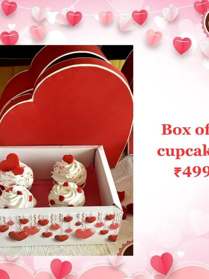 A box of four delicate cupcakes topped with whipped cream and tiny hearts, presented in a beautiful heart-themed box for Valentine's Day.